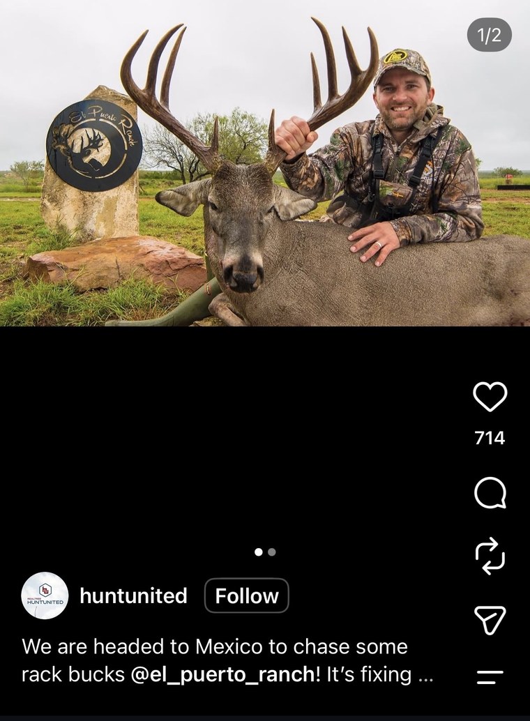 Hunter posing with a whitetail buck by the ranch entrance sign